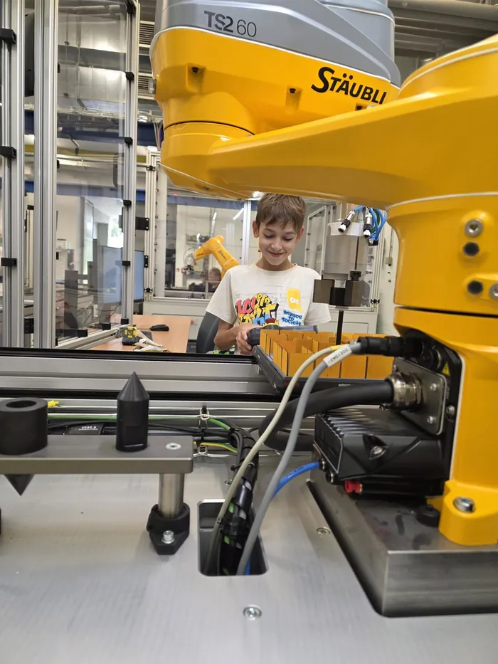 Účastník u robotického pracoviště v laboratoři.